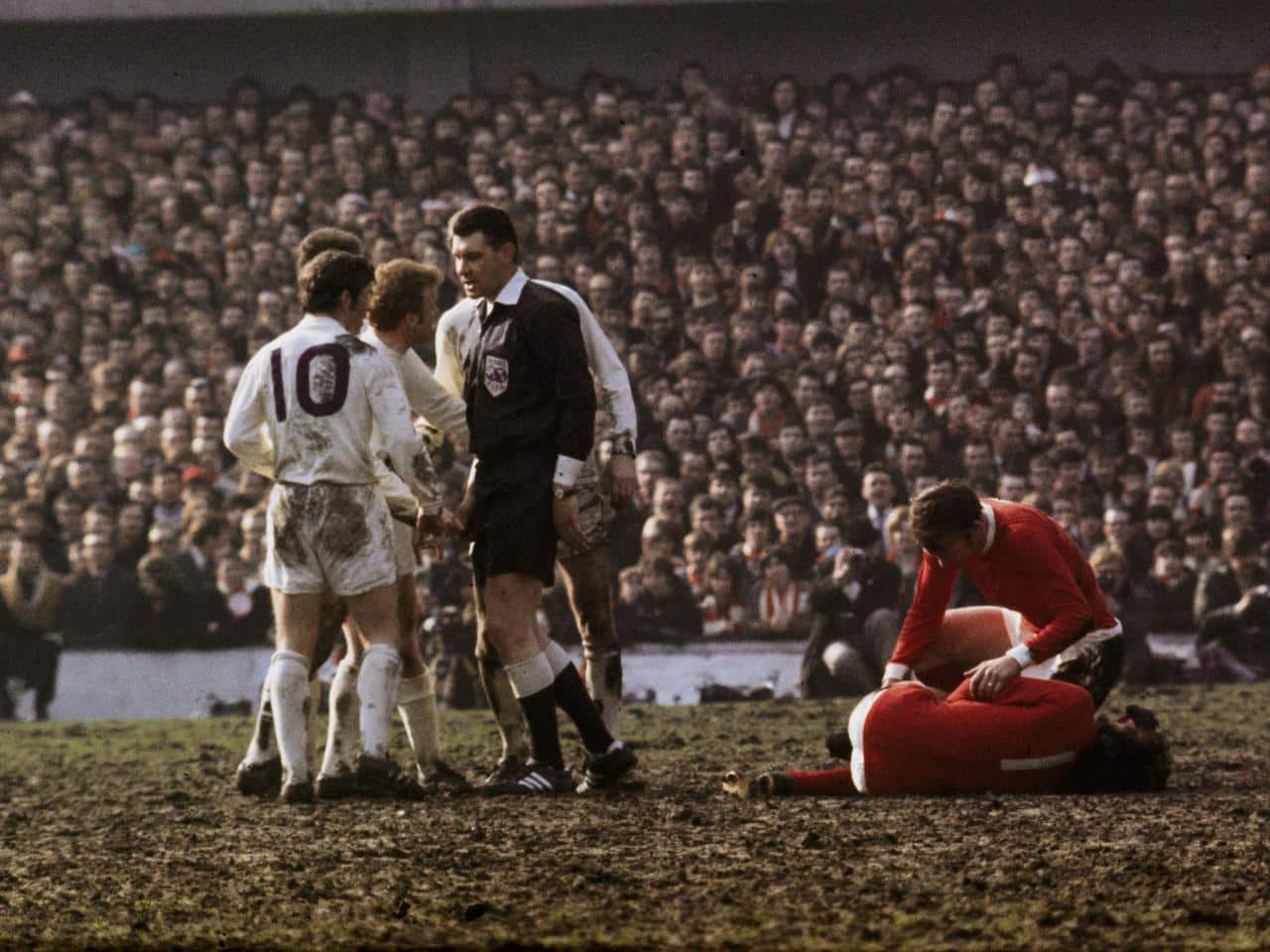 1970:  Referee Jack Taylor talks to Leeds United's Billy Bremner (1942 -1997) as Manchester United's Pat Crerand attends to injured team mate George Best.  (Photo by A. Jones/Express/Getty Images)