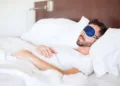 Portrait of a young man with a beard using a sleep mask to get some rest in a hotel