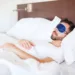 Portrait of a young man with a beard using a sleep mask to get some rest in a hotel