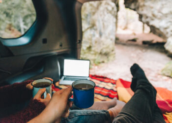 Couple laying in suv car trunk with view of rocky mountains