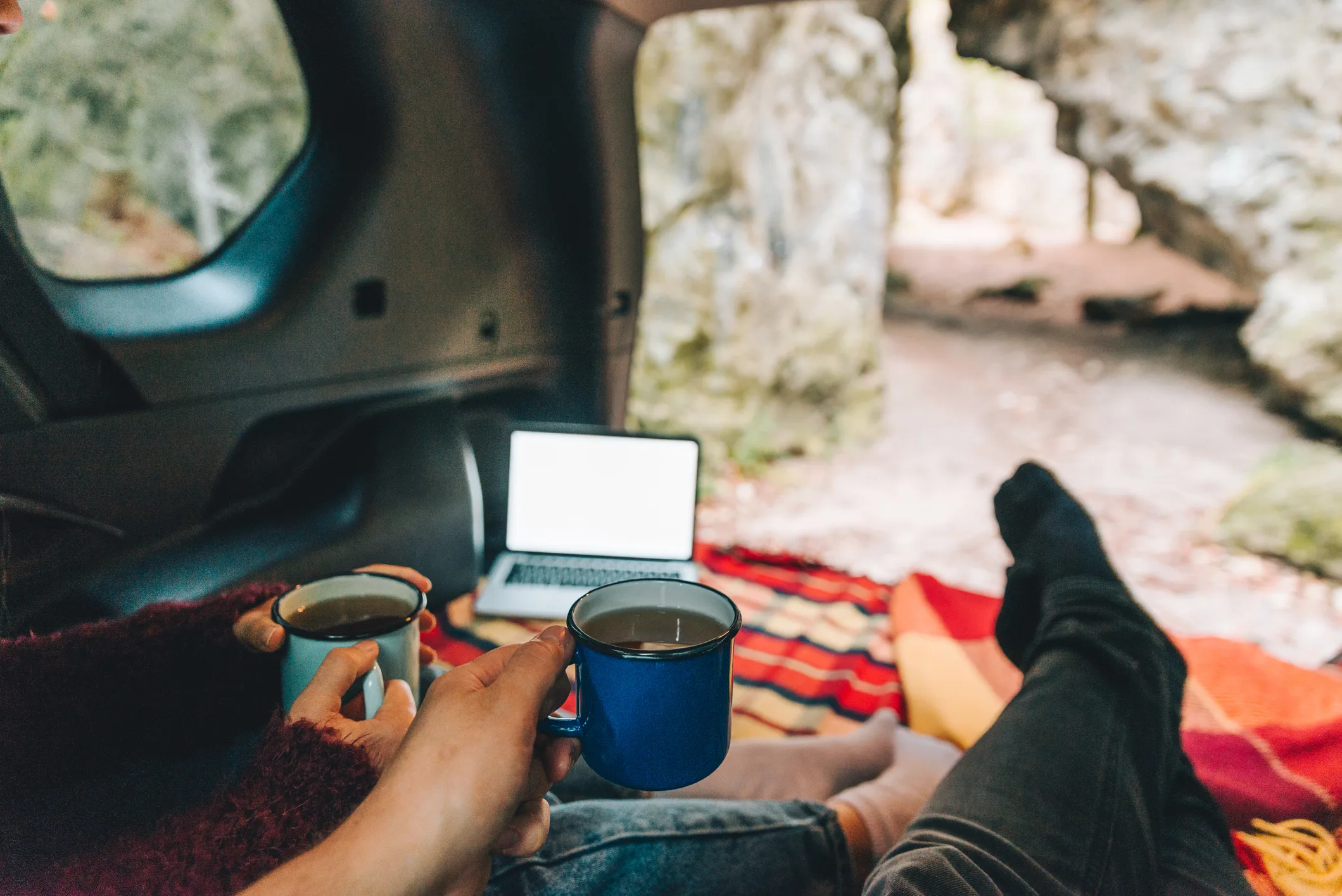 Couple laying in suv car trunk with view of rocky mountains